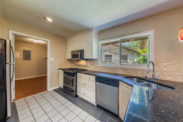 a kitchen with stainless steel appliances granite countertop a stove a sink and a refrigerator