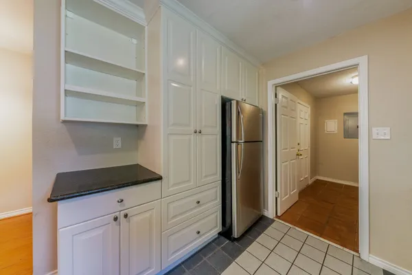 a kitchen with white cabinets and refrigerator