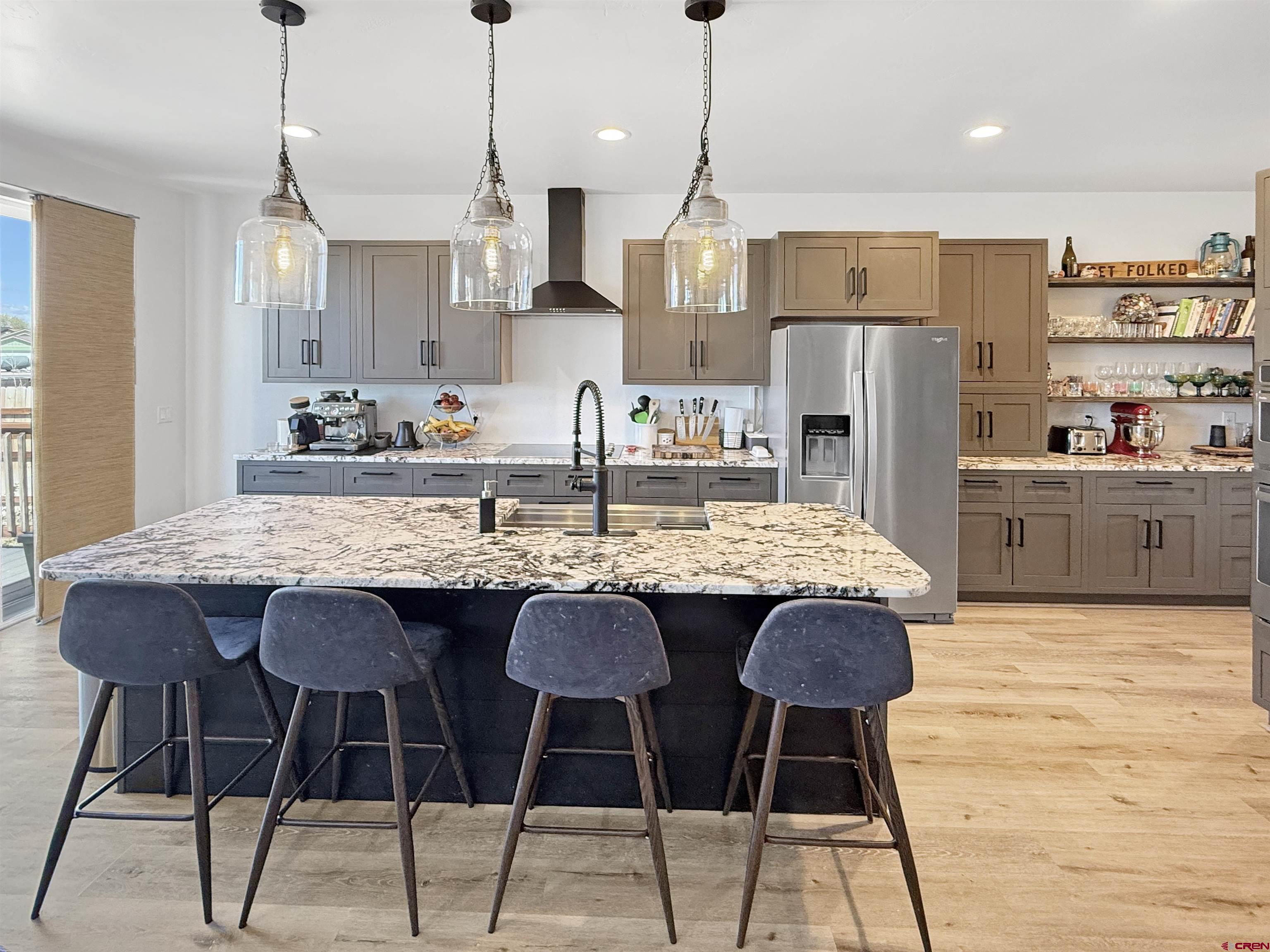 903 South Oak Street Cortez, CO 81321 - Photo 10 of 44 a kitchen with granite countertop kitchen island stainless steel appliances a dining table chairs and white cabinets
