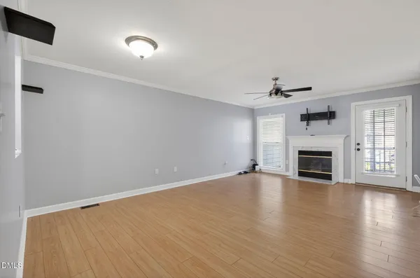 an empty room with wooden floor fireplace and windows