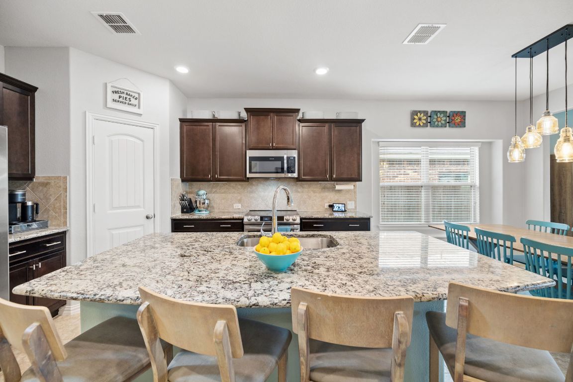 454 Shale Circle Buda, TX 78610 - Photo 4 of 27 a kitchen with a dining table chairs and refrigerator