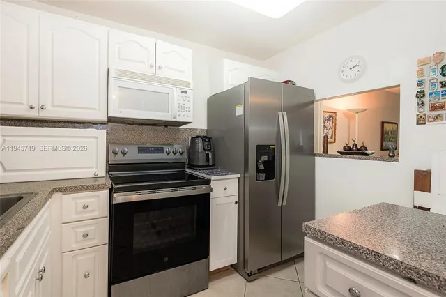 a kitchen with granite countertop white cabinets and stainless steel appliances