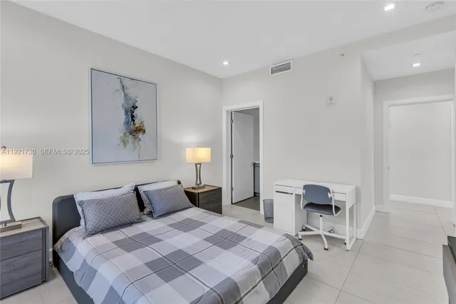 a bedroom with a bed and a lamp on dresser