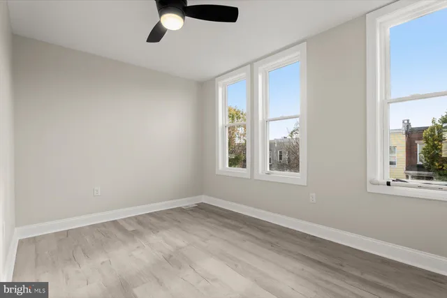 a view of an empty room with a window and wooden floor
