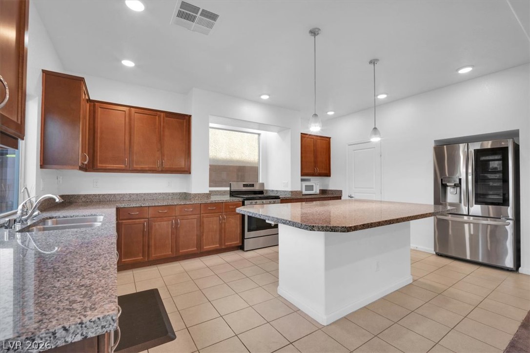 8046 Noble Ridge Street Las Vegas, NV 89139 - Photo 12 of 34 An inviting kitchen features a central island, rich cabinetry, and sleek stainless steel appliances.