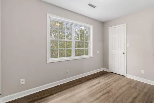 an empty room with wooden floor and windows