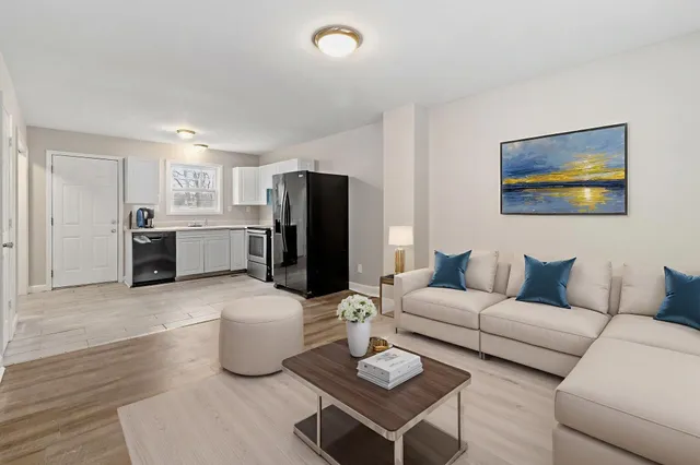a living room with furniture a refrigerator and kitchen view
