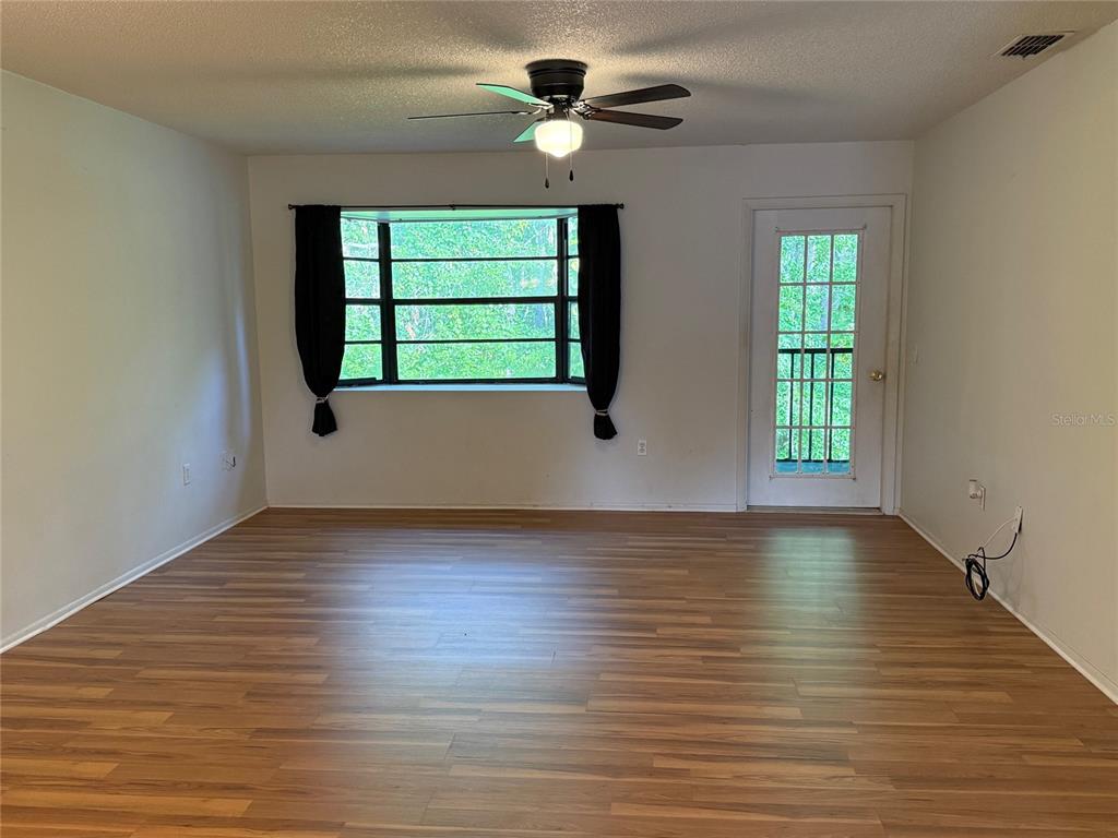 12155 Environmental Drive, Unit 6 New Port Richey, FL 34654 - Photo 12 of 31 an empty room with wooden floor chandelier fan and windows