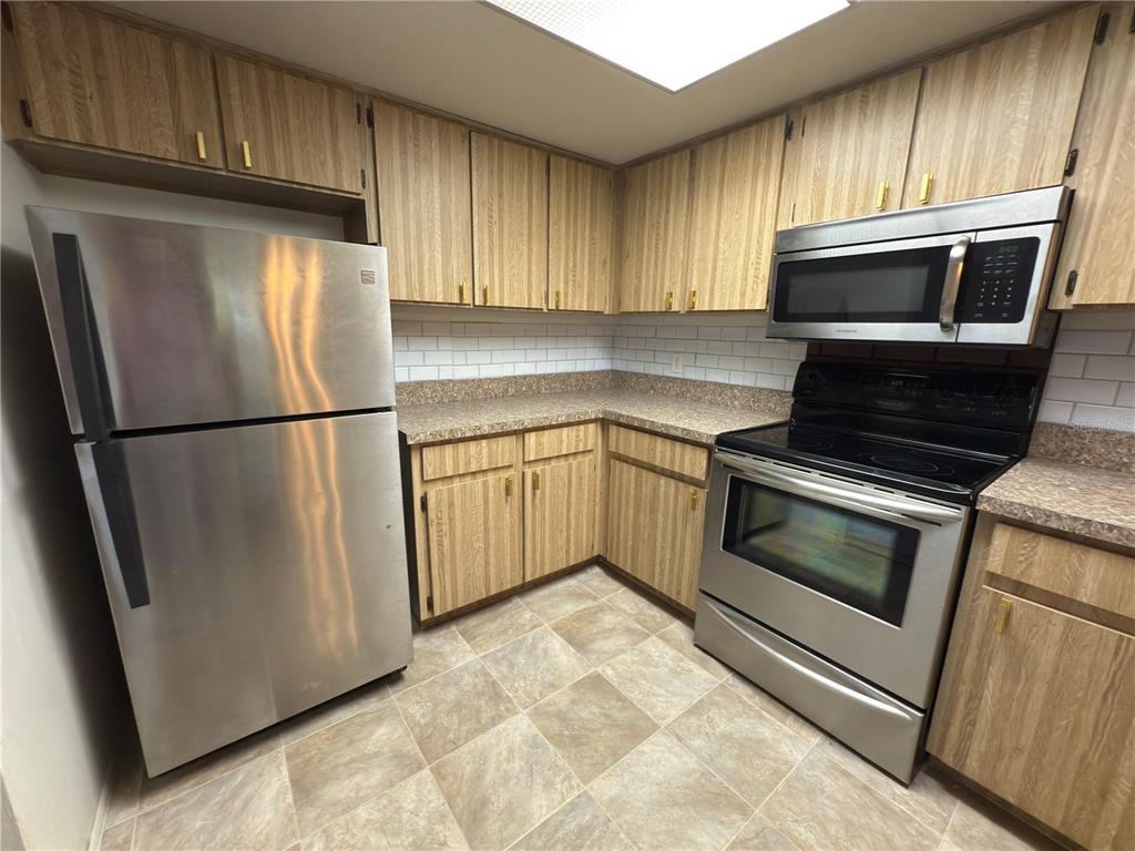 12155 Environmental Drive, Unit 6 New Port Richey, FL 34654 - Photo 9 of 31 a kitchen with granite countertop a refrigerator stove and microwave