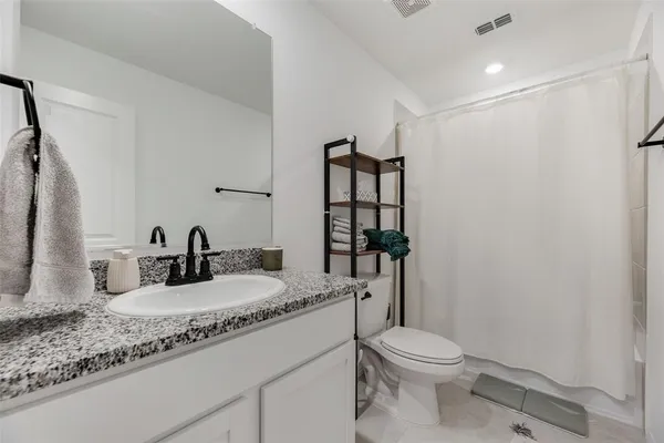 a bathroom with a granite countertop sink toilet and shower