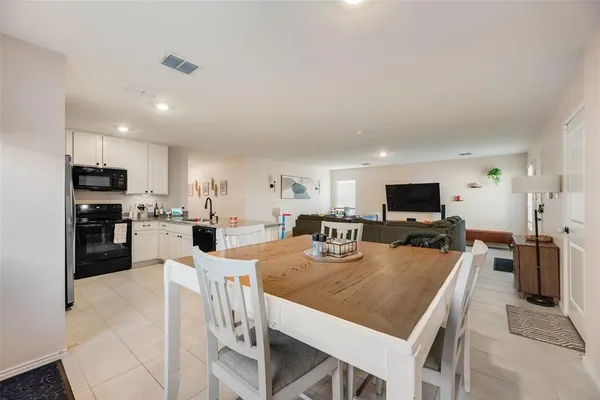 a large kitchen with a table chairs refrigerator and microwave
