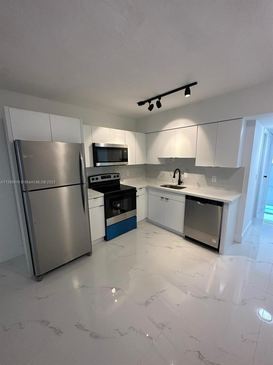 a kitchen with stainless steel appliances granite countertop a refrigerator a stove a sink and a microwave