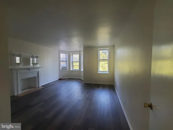 an empty room with wooden floor fireplace and windows