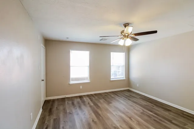 an empty room with a window and a chandelier fan