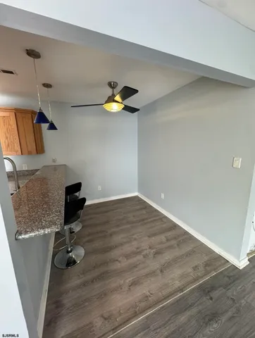 a view of a hallway with wooden floor and a bathroom