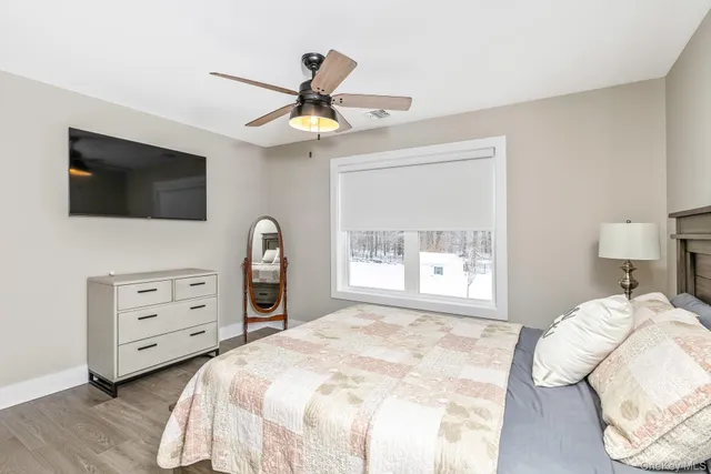 a bedroom with a bed a dresser and a flat screen tv