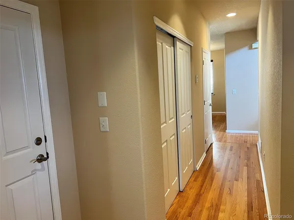 a view of a hallway with wooden floor and a bathroom