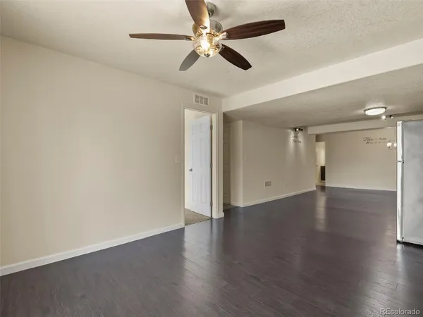 an empty room with wooden floor ceiling fan and window