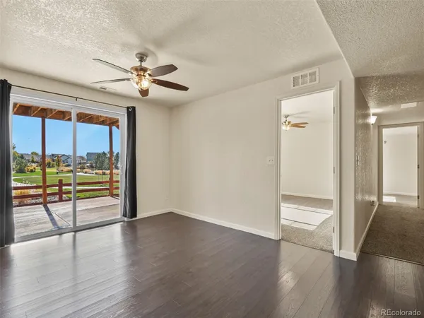 an empty room with wooden floor fan and windows
