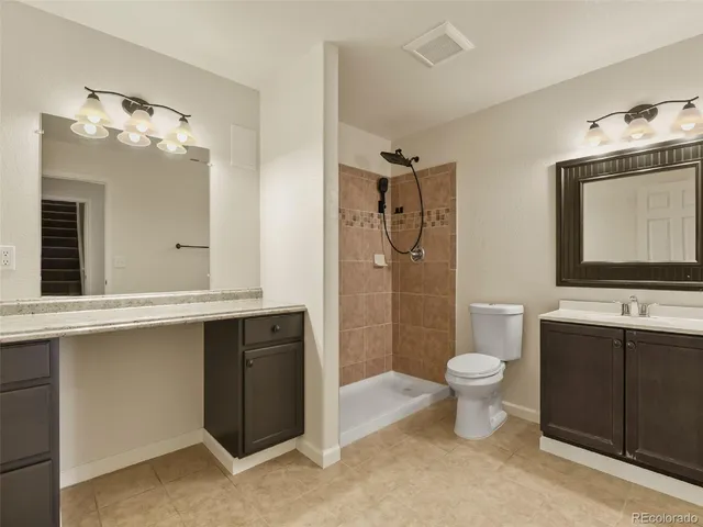 a bathroom with a toilet sink double vanity and mirror
