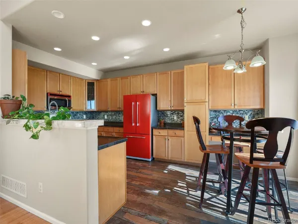 a kitchen with stainless steel appliances kitchen island granite countertop a table chairs and a refrigerator