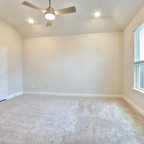 an empty room with windows and chandelier fan