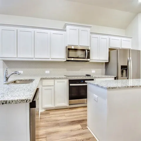 a kitchen with granite countertop a sink stove and microwave