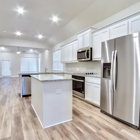 a kitchen with stainless steel appliances granite countertop a refrigerator a stove a sink and a microwave
