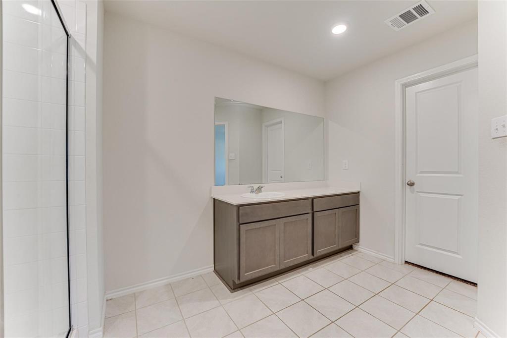 517 Milo Way Royse City, TX 75189 - Photo 6 of 34 Bathroom vanity featuring a single basin sink, light-toned countertop, and dark wood-finish cabinetry