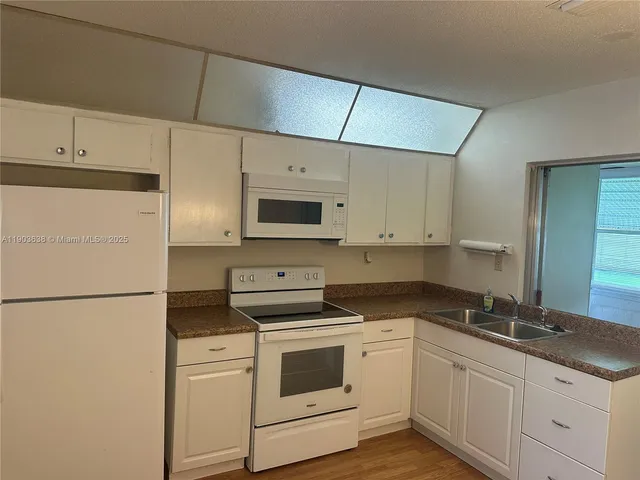 a kitchen with granite countertop white cabinets and white appliances