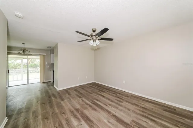 a view of empty room with wooden floor and ceiling fan