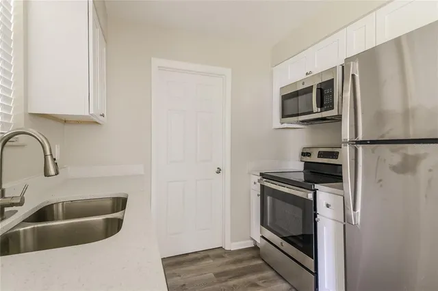 a kitchen with stainless steel appliances granite countertop a sink a stove a microwave and refrigerator