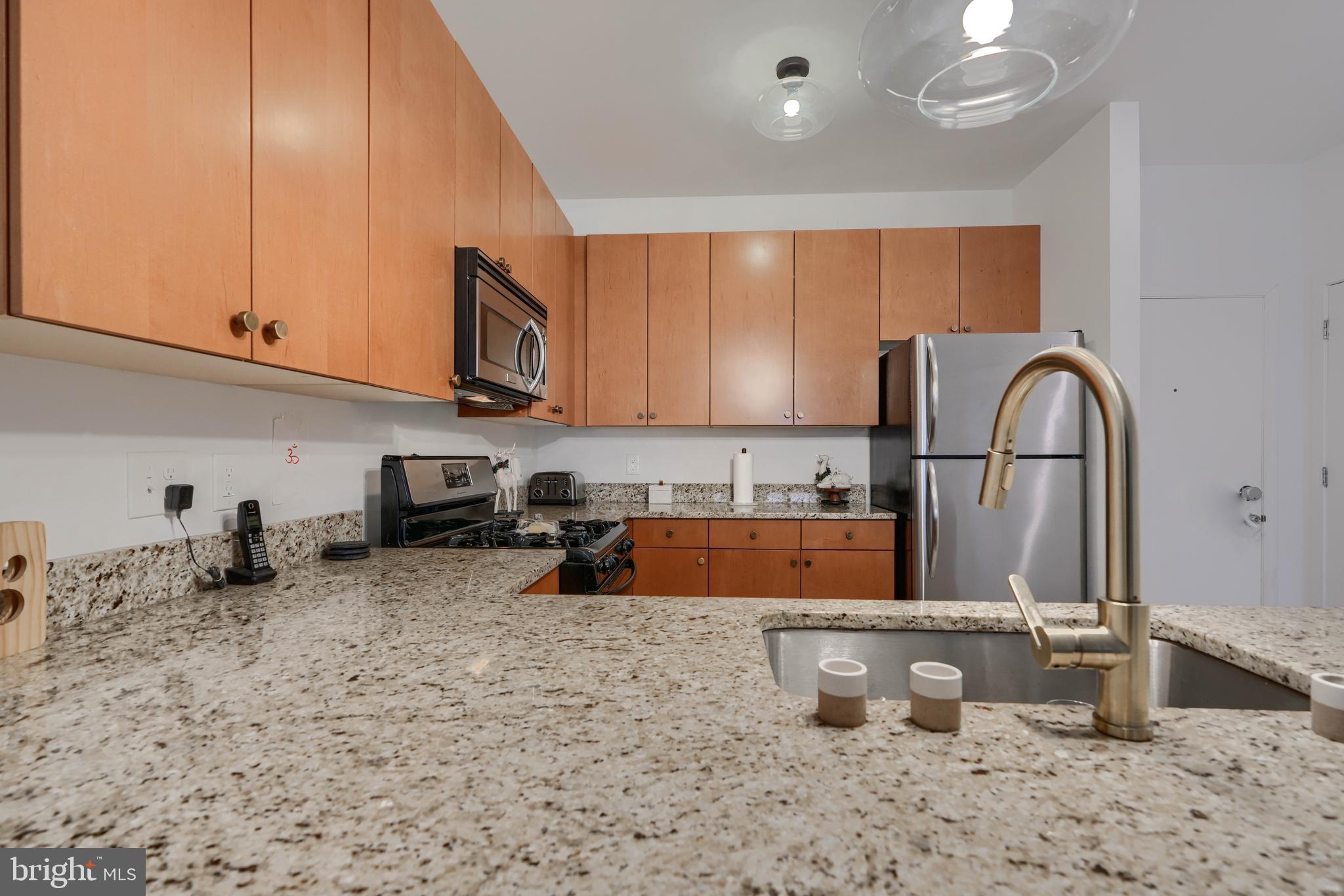 3201 St Paul Street, Unit 210 Baltimore, MD 21218 - Photo 11 of 38 a kitchen with stainless steel appliances granite countertop a sink a stove and a microwave