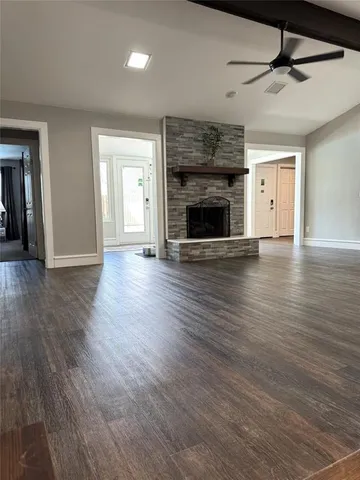 a view of an empty room with wooden floor fireplace and a window