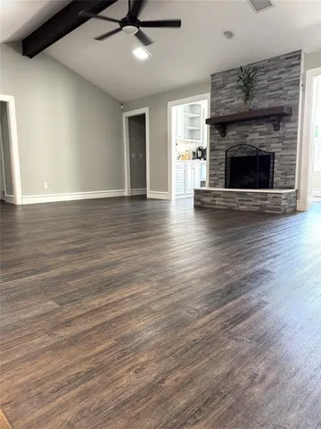 an empty room with wooden floor fireplace and windows