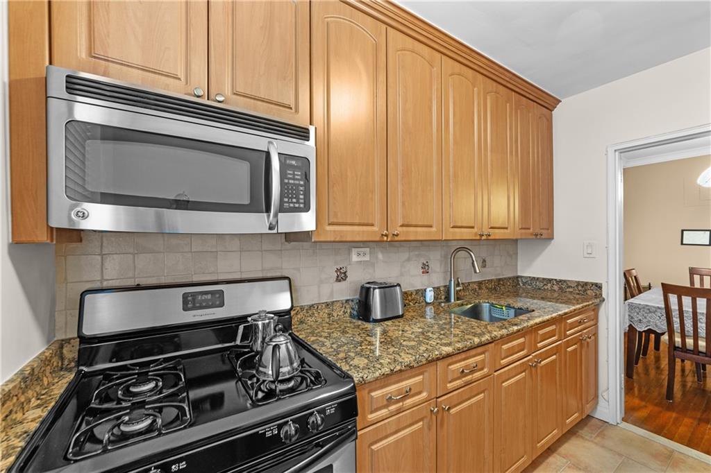 9201 Shore Road, Unit C508 Brooklyn, NY 11209 - Photo 14 of 15 a kitchen with stainless steel appliances granite countertop a stove and a microwave