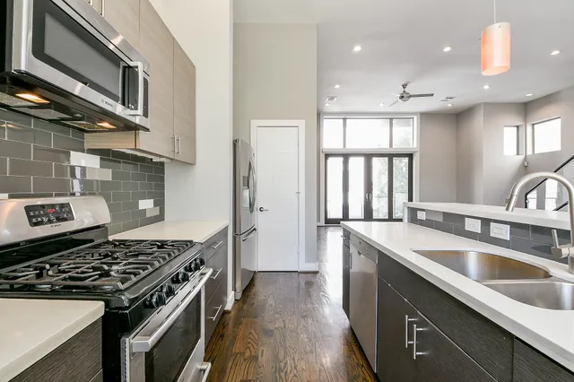 a kitchen that has a sink wooden floor stainless steel appliances and cabinets