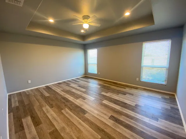 an empty room with wooden floor and windows