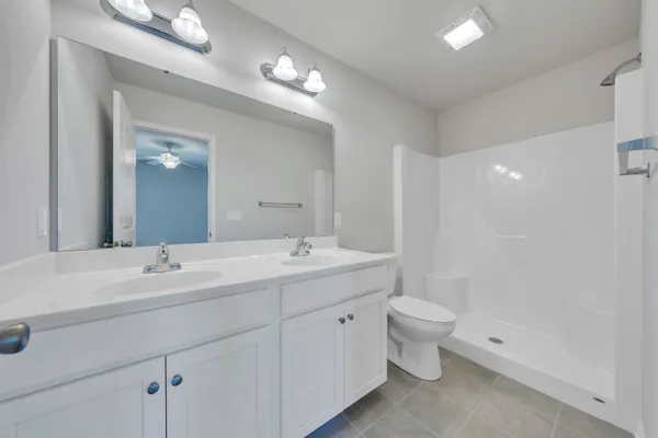 a spacious bathroom with a double vanity sink toilet and a mirror