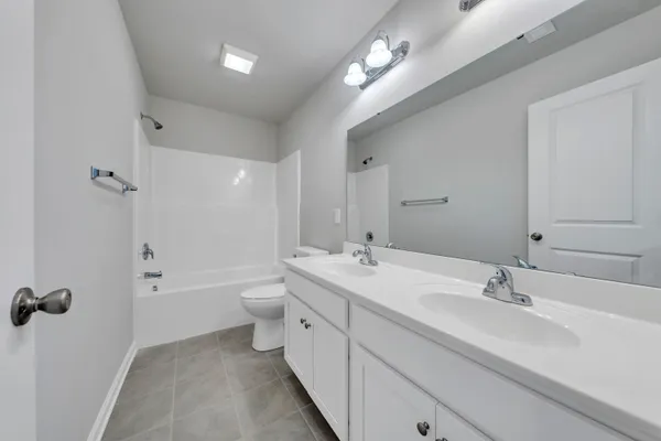 a spacious bathroom with a double vanity sink a toilet and shower