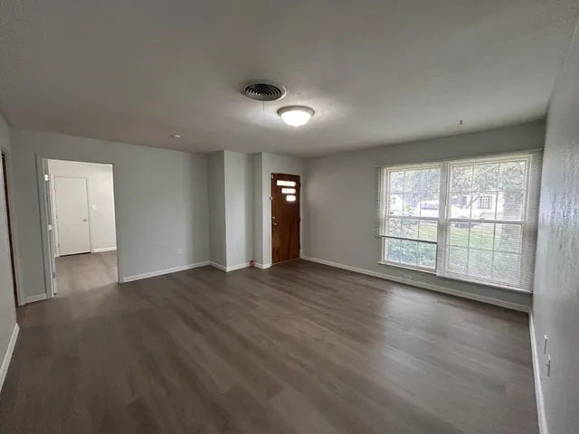 a view of an empty room with wooden floor and a window