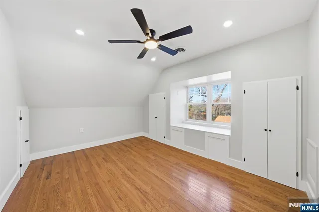 a view of empty room with wooden floor and ceiling fan