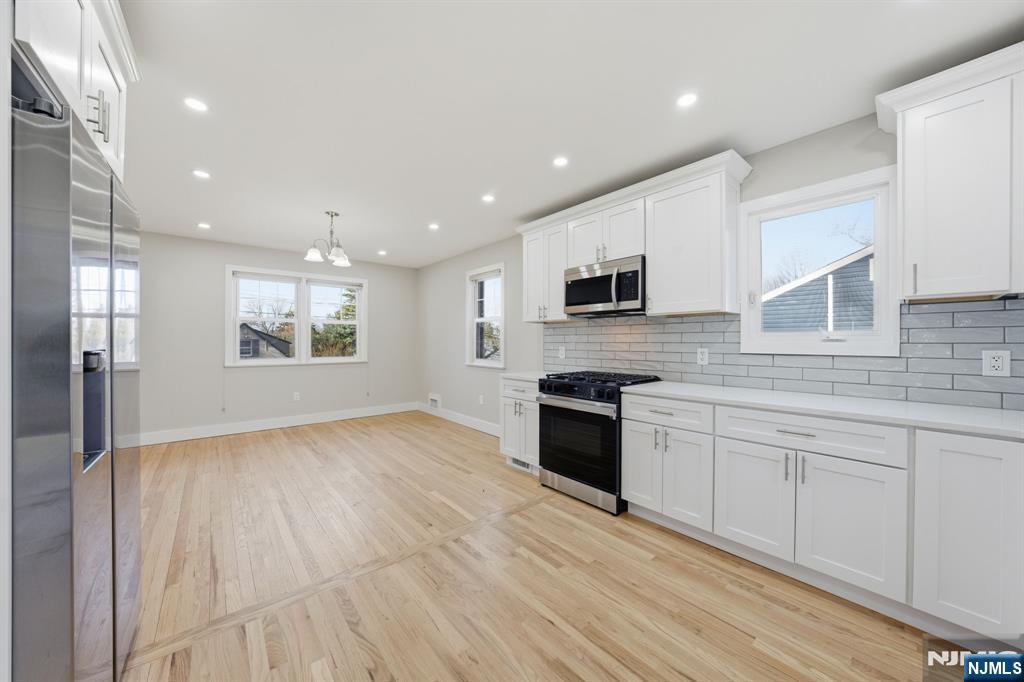25 Forest Street Closter, NJ 07624 - Photo 8 of 48 a kitchen with granite countertop a stove top oven a sink dishwasher and a refrigerator with wooden floor