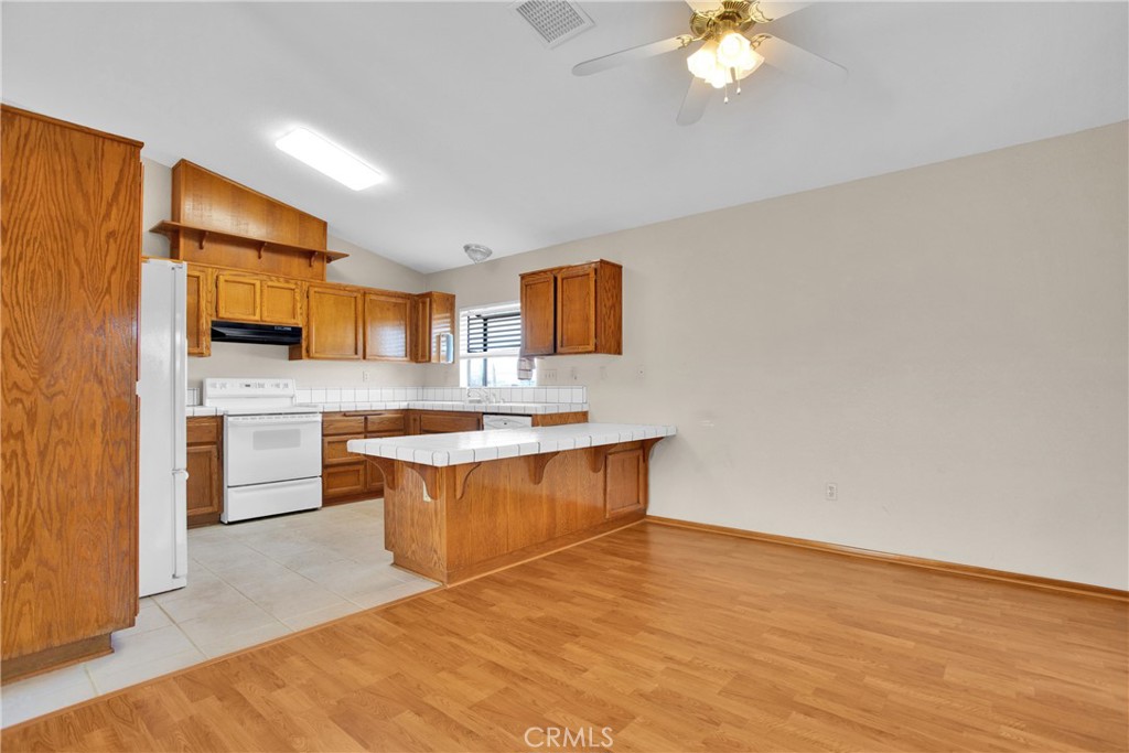 22544 Ojai Road Apple Valley, CA 92308 - Photo 3 of 20 a kitchen with stainless steel appliances granite countertop a sink a stove a refrigerator cabinets and living room view