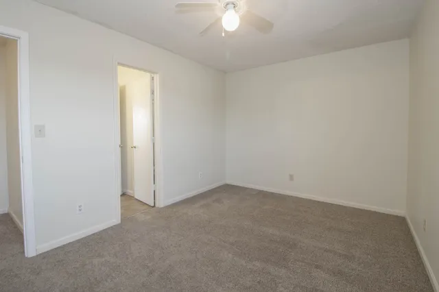 an empty room with windows and fan