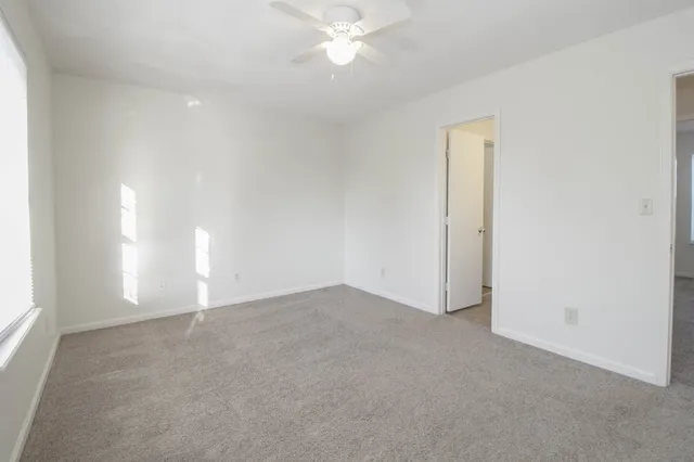 an empty room with windows and fan