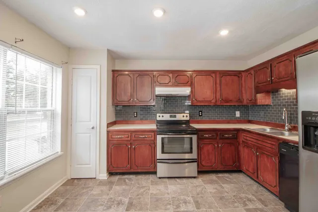 a kitchen with stainless steel appliances granite countertop a refrigerator a sink and a stove