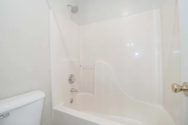 an empty room with a chandelier fan and windows