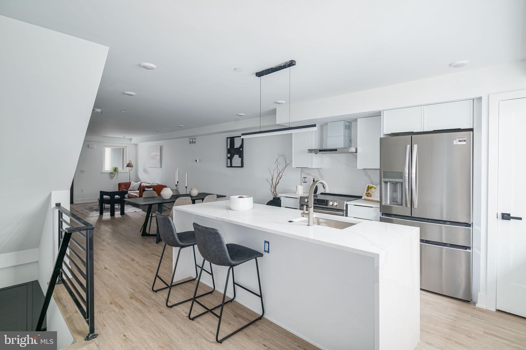 a kitchen with stainless steel appliances a refrigerator a sink a stove a dining table and chairs