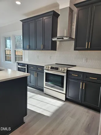 a view of kitchen with stainless steel appliances kitchen island hard wood floors and fireplace